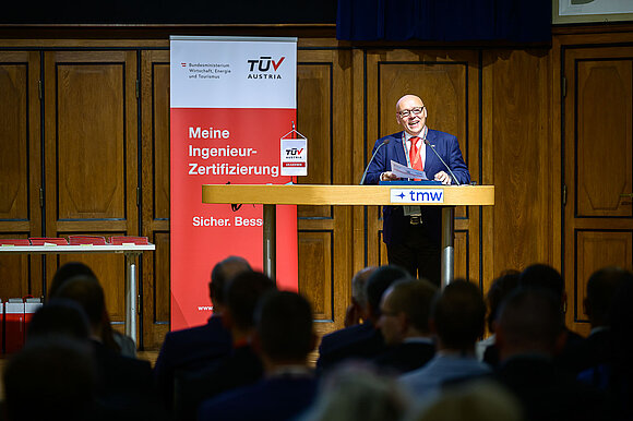 Mann hält Rede auf einer Bühne.