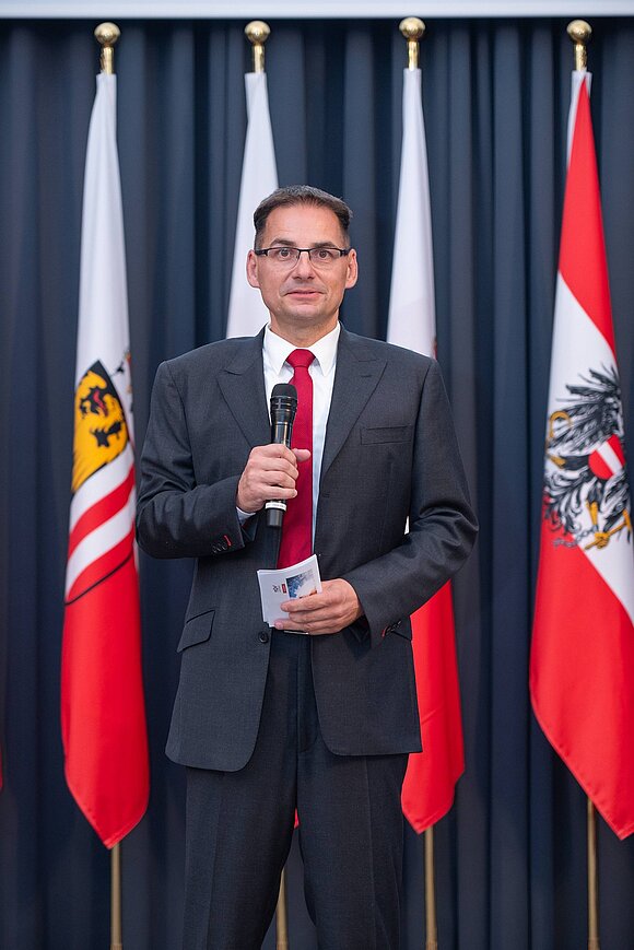Herr im Anzug mit Mikrofon in der Hand