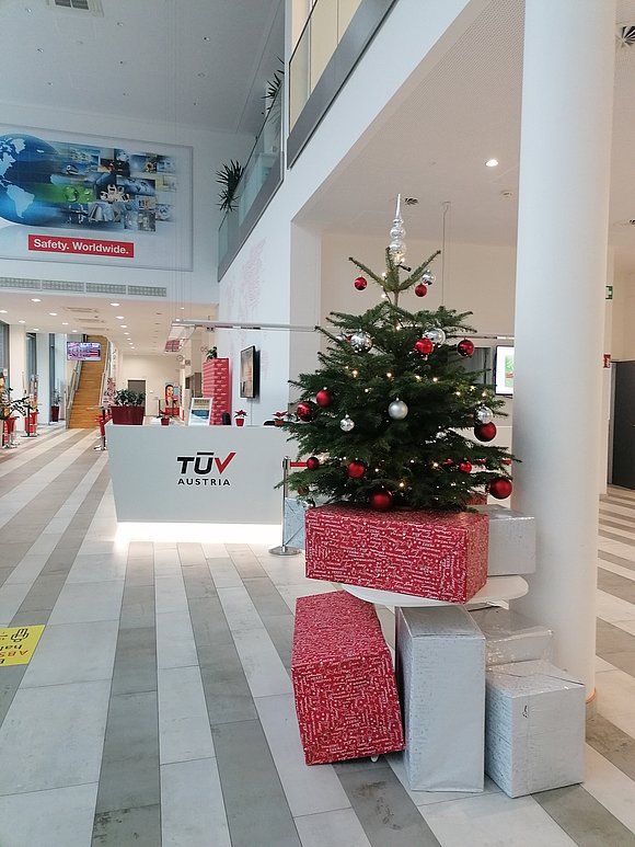 Ein Weihnachtsbaum in der Lobby des TÜV AUSTRIA, umgeben von Geschenkkartons, die festliche Stimmung verbreiten.