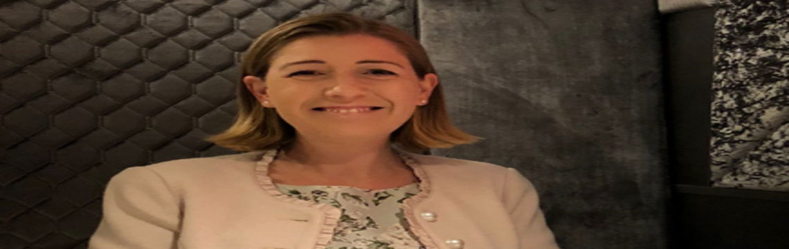 Eine Frau in einem weißen Blazer lächelt entspannt in die Kamera