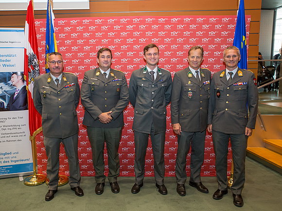 Gruppenfoto vor TÜV AUSTRIA Pressewand. Vier Herren in Uniformen.