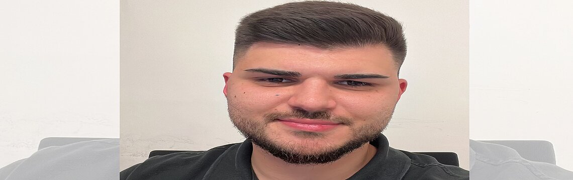 Ein Bartträger in schwarzem Shirt posiert selbstbewusst vor der Kamera.