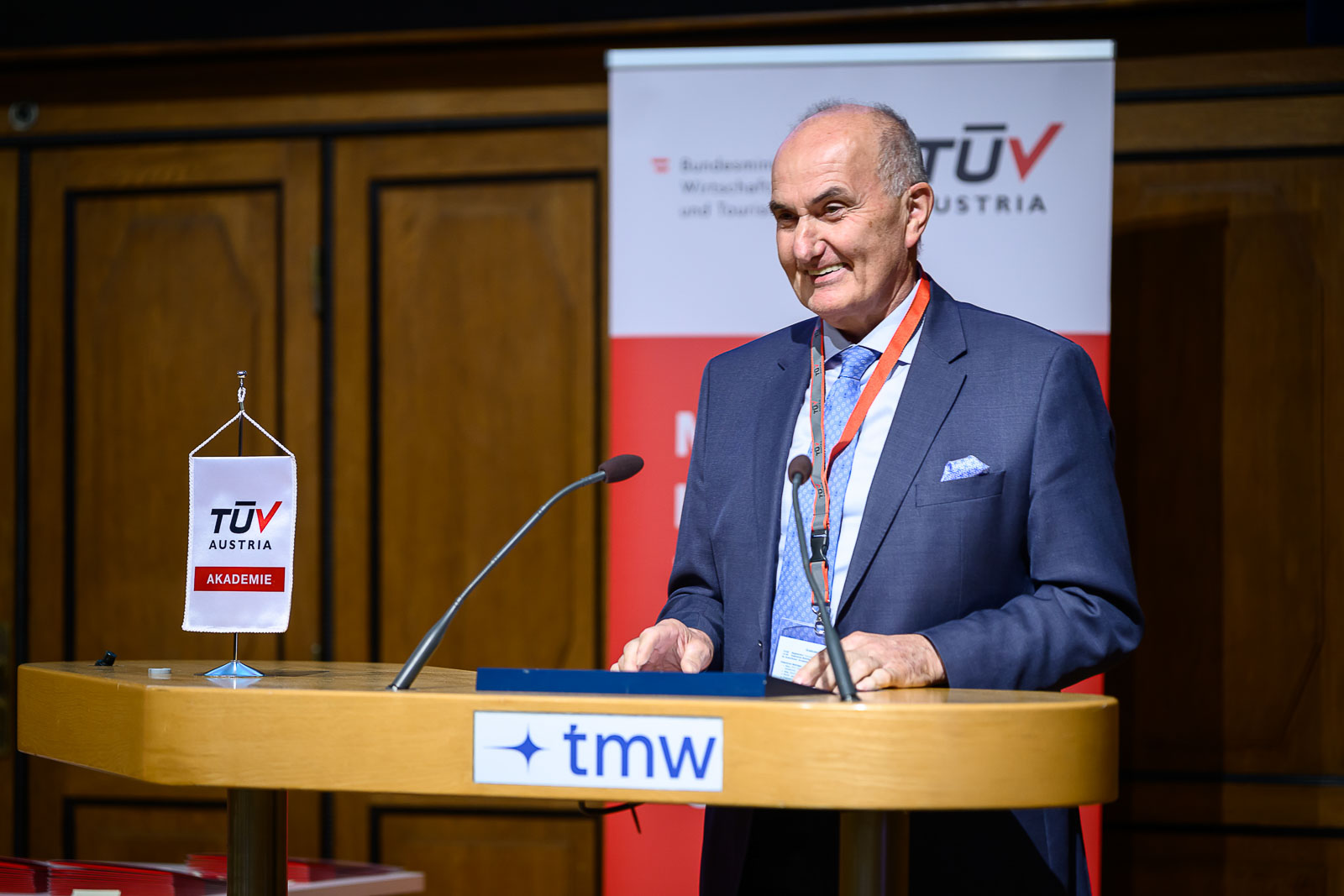 <br /> Mann im Anzug hält Rede auf Bühne.