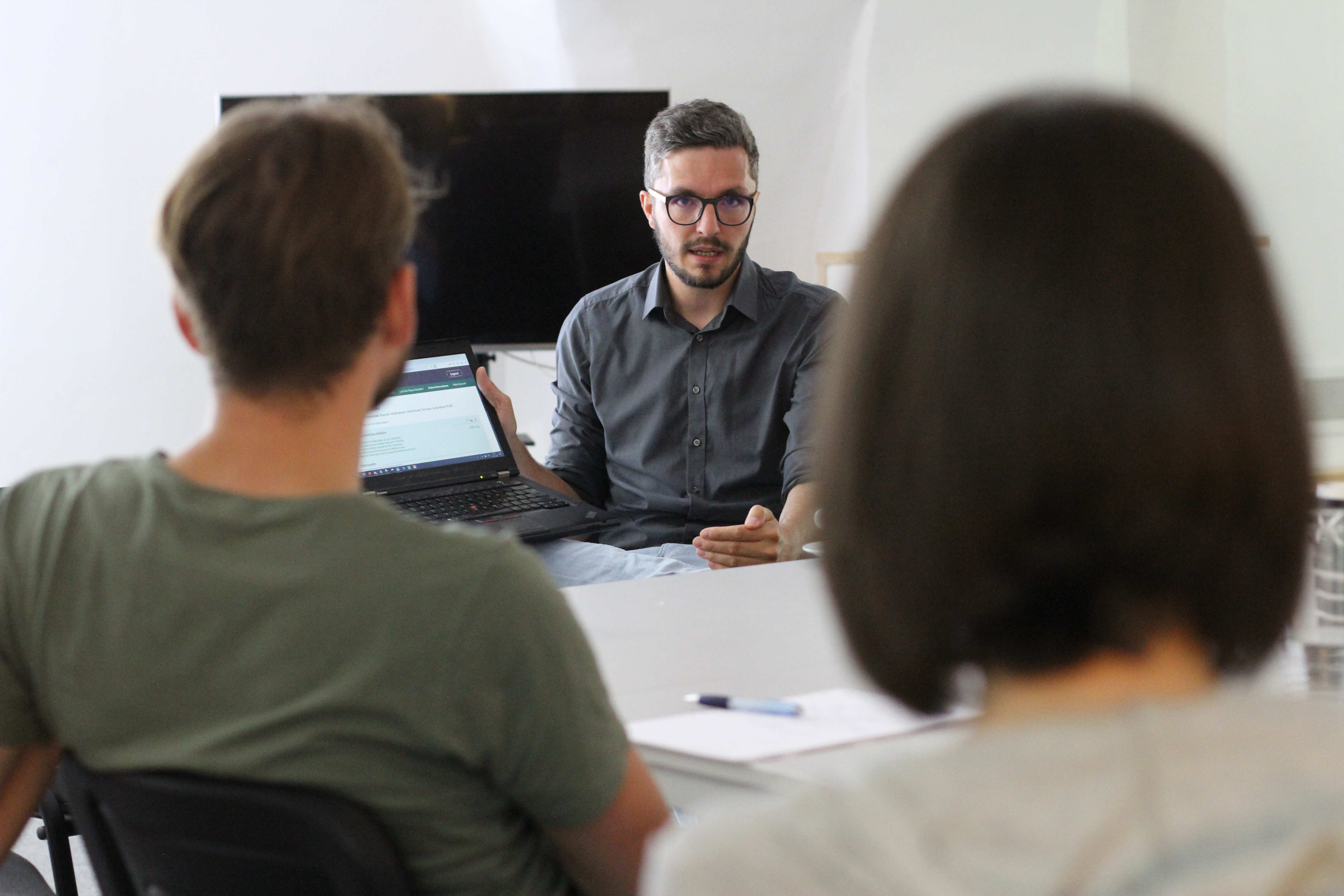 Ein Mann spricht zu 2 Menschen während eines Meetings.