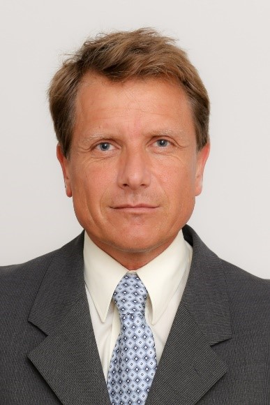 Ein Mann in Anzug und Krawatte schaut direkt in die Kamera und strahlt Selbstbewusstsein aus.